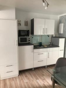 a kitchen with white cabinets and a microwave at Gäste-Apartment "Carpe Diem" in Osterburg