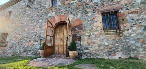 um antigo edifício de pedra com uma porta de madeira em Masia Can Bachs em Sant Pere de Vilamajor