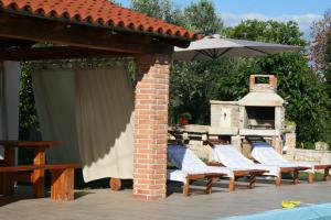 um pátio com cadeiras, um guarda-sol e uma lareira em DAMJANIĆ HOLIDAY HOUSE em Brtonigla