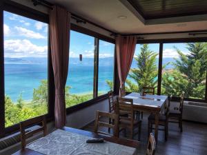 a dining room with a table and chairs and large windows at Hotel Camping Lin in Pogradec