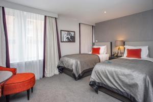 um quarto de hotel com duas camas e uma cadeira vermelha em Ten Hill Place em Edimburgo