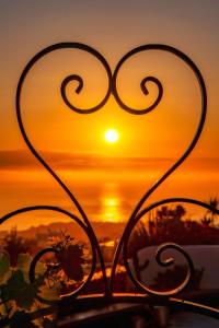 a view of the sunset through a forged fence at San Marino Suites by Calm Collection in Fira