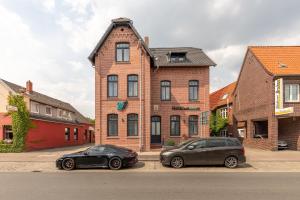 two cars parked in front of a brick building at 24/7 Selfcheckin in Leer