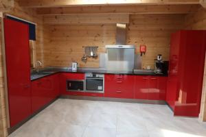 een keuken met rode kasten in een houten keuken bij Familiehuis Klokkenweide in Loon op Zand