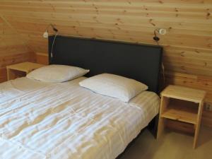 ein Schlafzimmer mit einem Bett mit zwei Kissen und zwei Tischen in der Unterkunft Familiehuis Klokkenweide in Loon op Zand