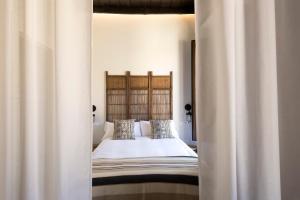 una camera da letto con un letto con lenzuola e cuscini bianchi di Apartamentos Simba a Málaga