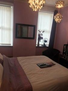 a bedroom with a bed and a chandelier and windows at Sutton Park Guest House in Blackpool
