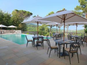 a group of tables and chairs with umbrellas next to a pool at Hotel Villa Casanova in Lucca