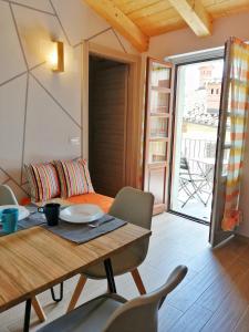 - Mesa de comedor y sillas en una habitación con balcón en FIORDAELISA APARTMENT, en Monforte dʼAlba