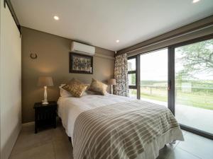 a bedroom with a bed and a large window at Equestre BnB in Pietermaritzburg