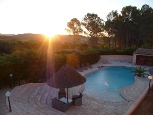 a swimming pool with a sunset in the background at La Bastide Des Selves in Draguignan +28 photos
