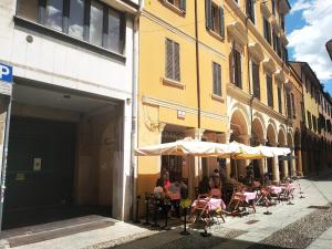 grupa ludzi siedzących przy stołach pod parasolami na ulicy w obiekcie 13- Tourist House Bologna Pratello - Self check-in w Bolonii