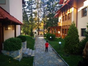 Un niño pequeño de pie en el patio de una casa. en Apartman šumski vilenjak, en Zlatibor