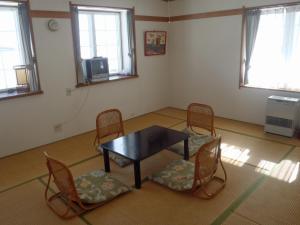 um quarto com uma mesa e cadeiras e uma televisão em Mont Cervin em Myoko