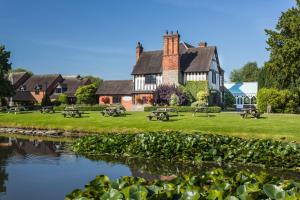 uma casa com um lago em frente em The Moat House em Stafford