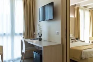 a hotel room with a desk and a television on the wall at Hotel Alexander in Mestre