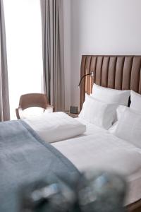 1 dormitorio con 1 cama con sábanas blancas y silla en Aiden by Best Western Biberach en Biberach an der Riß