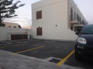 a car parked in a parking lot in front of a building at Acqua Chiara Appartamenti in San Vito lo Capo