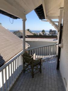 un banco en un balcón con vistas al océano en Ashby Manor Guest House, en Ciudad del Cabo