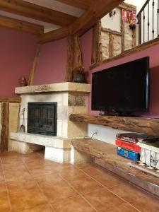 a living room with a fireplace and a flat screen tv at Casa Rural EL VALLECILLO in Valle de Tabladillo