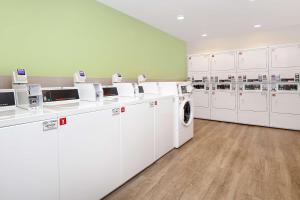 lavadero con lavadoras y secadoras blancas en WoodSpring Suites Carol Stream - Chicago, en Carol Stream