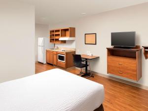 a bedroom with a bed and a desk with a television at WoodSpring Suites Merrillville in Merrillville