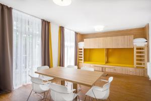 ein Esszimmer mit einem Holztisch und weißen Stühlen in der Unterkunft Szent Bernadett Családi Apartmanház in Siófok