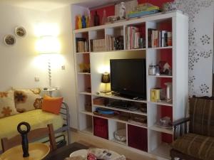 Manta Rota Beach, apartment in a villa, terrace,garden في مانتا روتا: غرفة معيشة مع رف كتاب مع تلفزيون