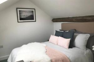 um quarto com uma cama com almofadas cor-de-rosa e brancas em A Cosy Cwtch retreat in the heart of the Clwydian Range em Cilcain