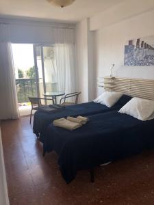 Un dormitorio con dos camas y una mesa con ventana. en Sol y Paz, en Torremolinos