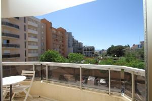 a balcony with a table and chairs and buildings at Soleil Bleu - T2 classé 3 étoiles en front de mer in Canet-en-Roussillon