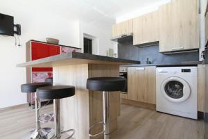 a kitchen with two bar stools and a washing machine at Soleil Bleu - T2 classé 3 étoiles en front de mer in Canet-en-Roussillon