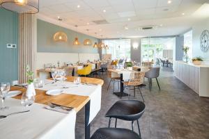 un restaurante con mesas blancas y sillas amarillas en Les Terrasses d'Atlanthal, en Anglet
