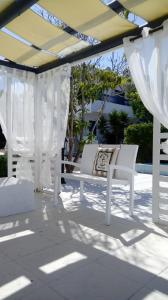 kilka białych krzeseł siedzących pod pergolą w obiekcie Flokkas Hotel Apartments w mieście Protaras