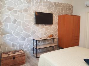 a bedroom with a tv on a stone wall at RosAmar in Bari