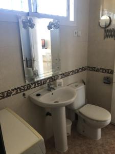 Un baño con lavabo, inodoro y espejo. en Sol y Paz, en Torremolinos