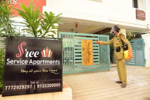un homme en uniforme debout devant un bâtiment dans l'établissement Sree Service apartments, à Tirupati
