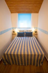 a large striped bed in a room with a window at Sossego da Natureza - Monte Alentejano in Grândola