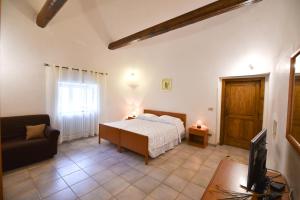 sypialnia z łóżkiem, kanapą i telewizorem w obiekcie Agriturismo il Ciliegeto w mieście Locorotondo