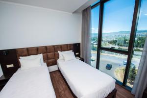 two beds in a room with a large window at Hotel Shine Palace in Tbilisi City