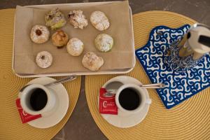 a table with two cups of coffee and a box of donuts at San Vito Accommodations in San Vito lo Capo