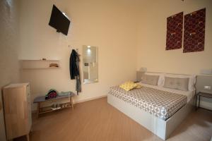 San Vito Accommodations في سان فيتو لو كابو: غرفة نوم مع سرير وتلفزيون على الحائط