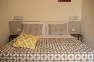 um quarto com uma cama grande e uma almofada amarela. em San Vito Accommodations em San Vito lo Capo