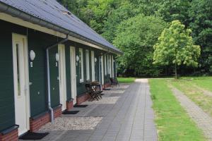 un bâtiment vert avec des chaises et un trottoir à côté de celui-ci dans l'établissement Horsetellerie Rheezerveen, à Hardenberg