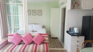 Dormitorio pequeño con cama con almohadas rosas en Summer Huahin Condo by Howard, en Hua Hin