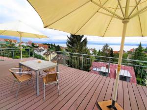 une terrasse en bois avec une table, des chaises et un parasol dans l'établissement BodenSEE Apartments Meersburg Sonnhalde, à Meersburg