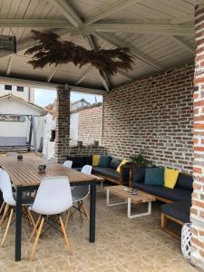 a patio with couches and tables and a brick wall at Casa Mediterana in 2 Mai