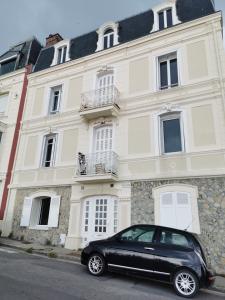une voiture noire garée devant un bâtiment dans l'établissement Les pieds dans l'eau, à Trouville-sur-Mer