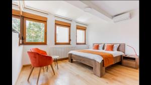 a bedroom with a bed and a chair and windows at Apartments RUBIK in Sarajevo