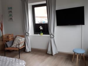 ein Wohnzimmer mit einem TV und einem Fenster in der Unterkunft Ferienwohnung Busdorf in Busdorf